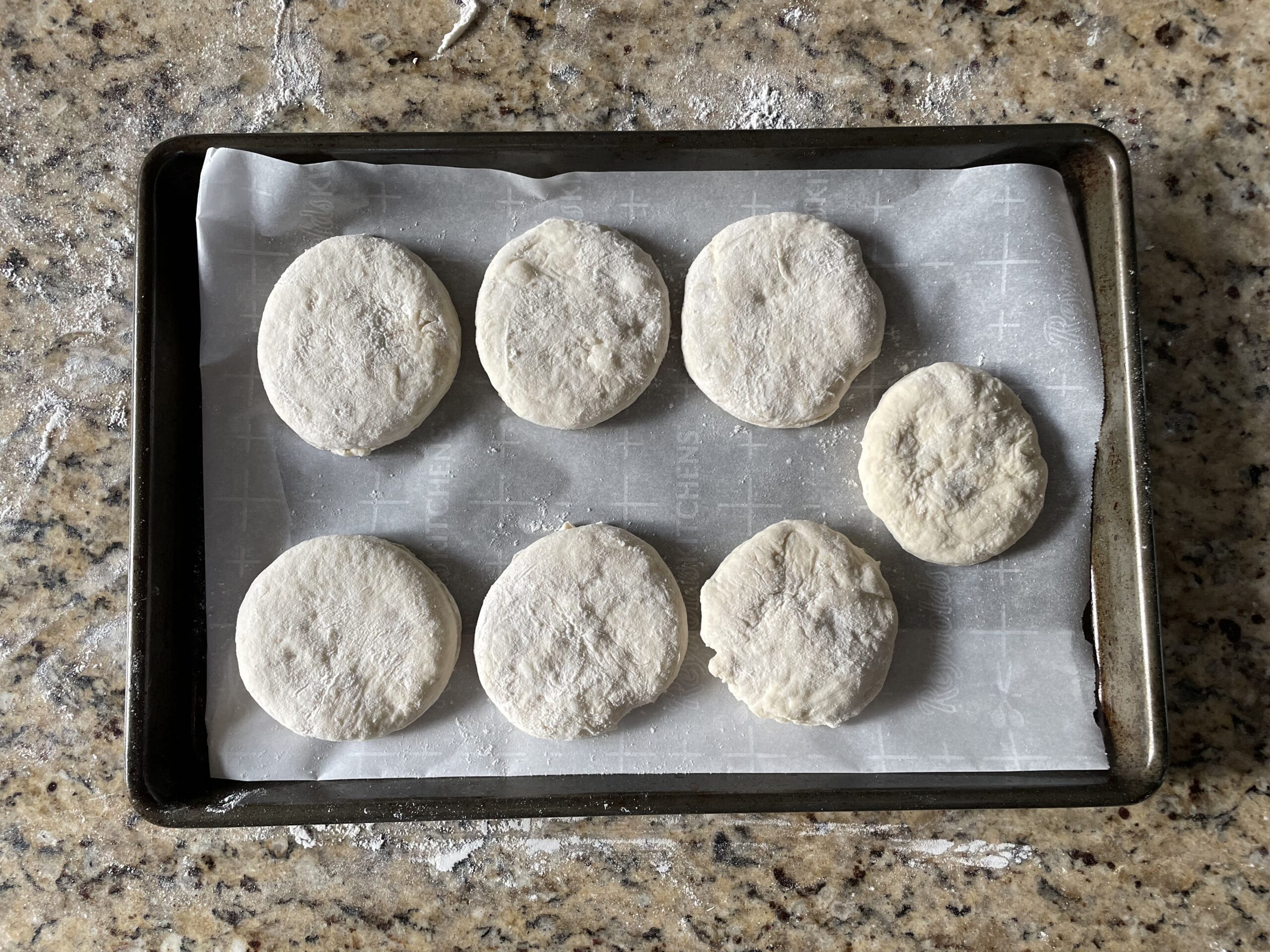 This photo shows the english muffins cut into circles and placed on a pan with parchment paper